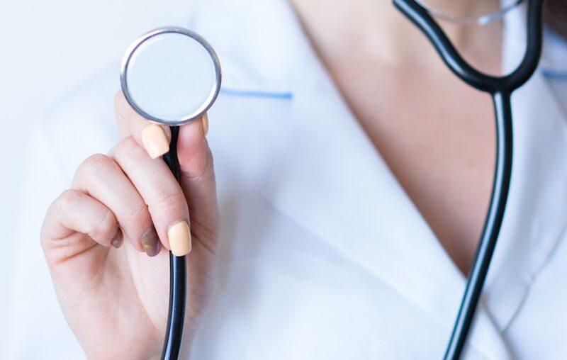 a woman in a white shirt holding a stethoscope