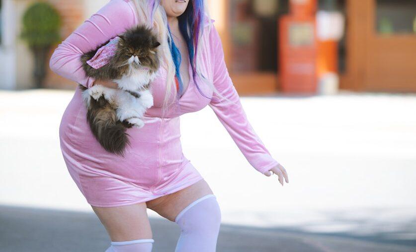 a woman in a pink dress holding a dog